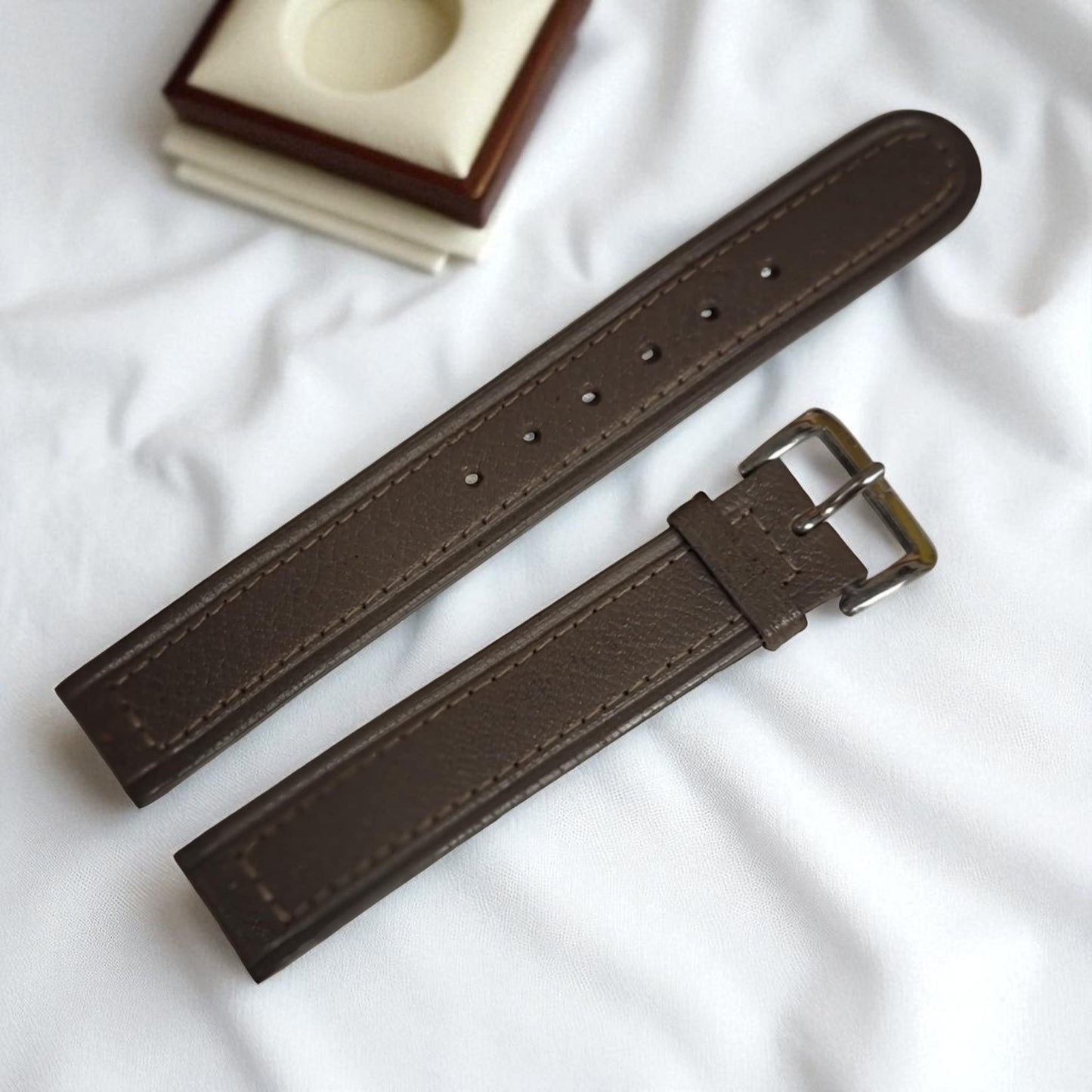 Brown leather watch strap with a buckle on a white background
