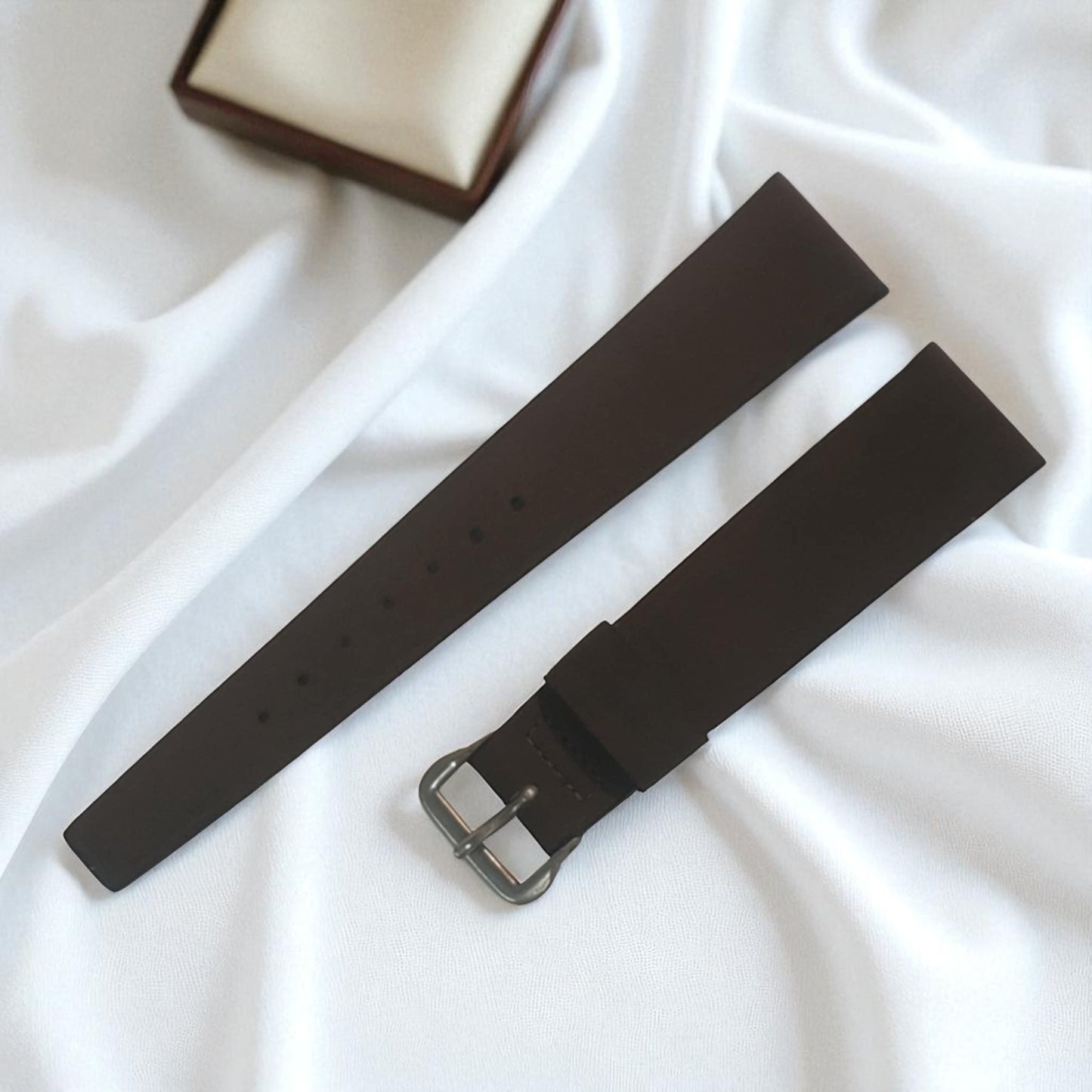 Black watch strap on a white fabric background