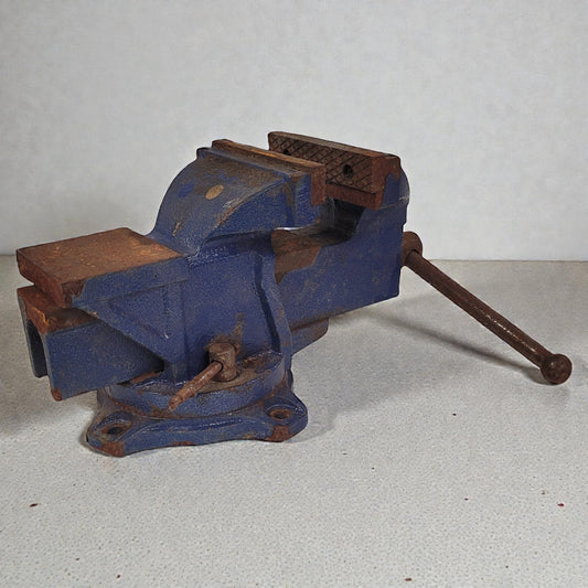 Vintage blue vise with rusted components on a light gray background