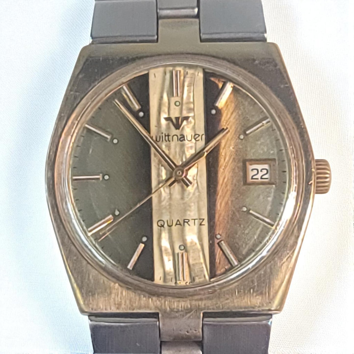 Vintage watch with a brown strap and metallic face on a light blue background