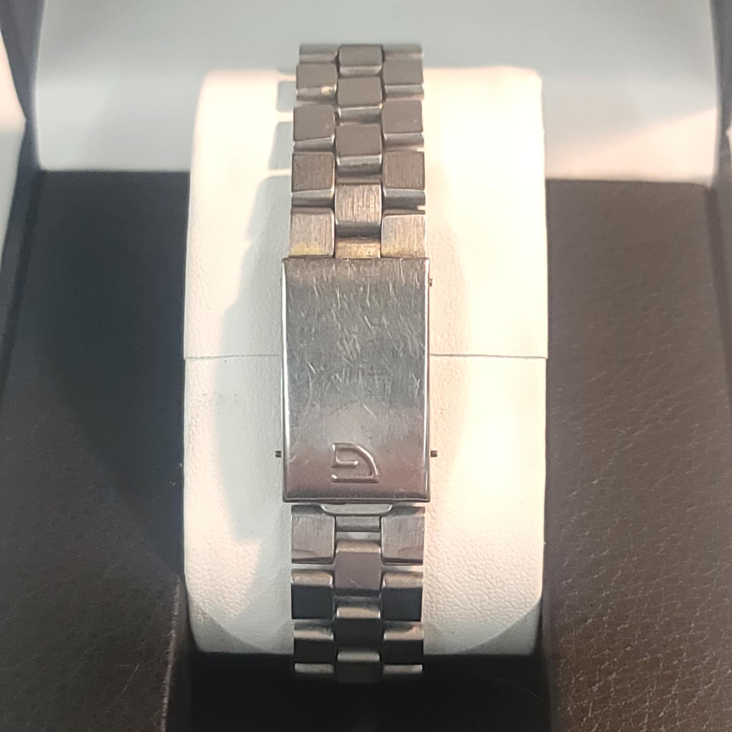 Silver watch with a brand logo on a white cushion