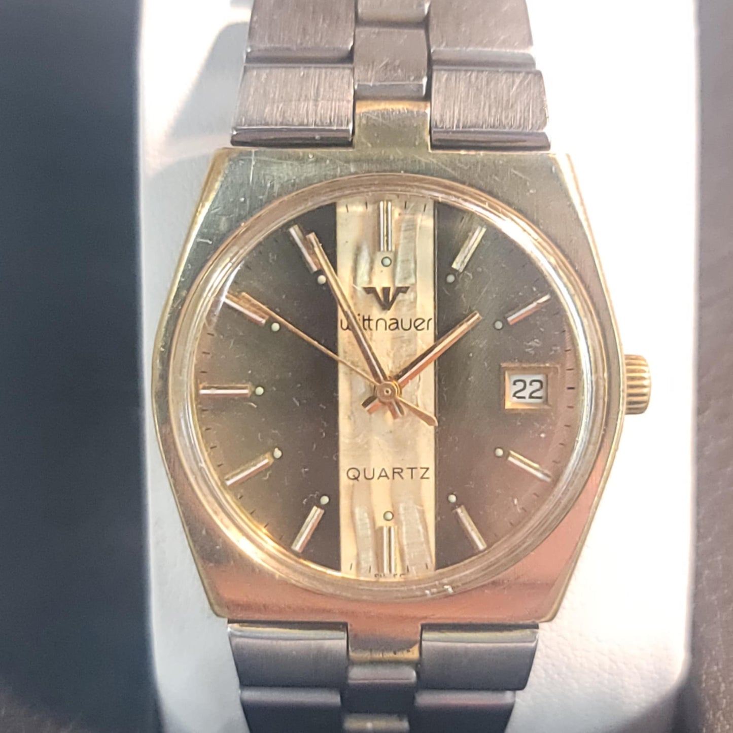 Vintage wristwatch with silver and gold band on a dark background