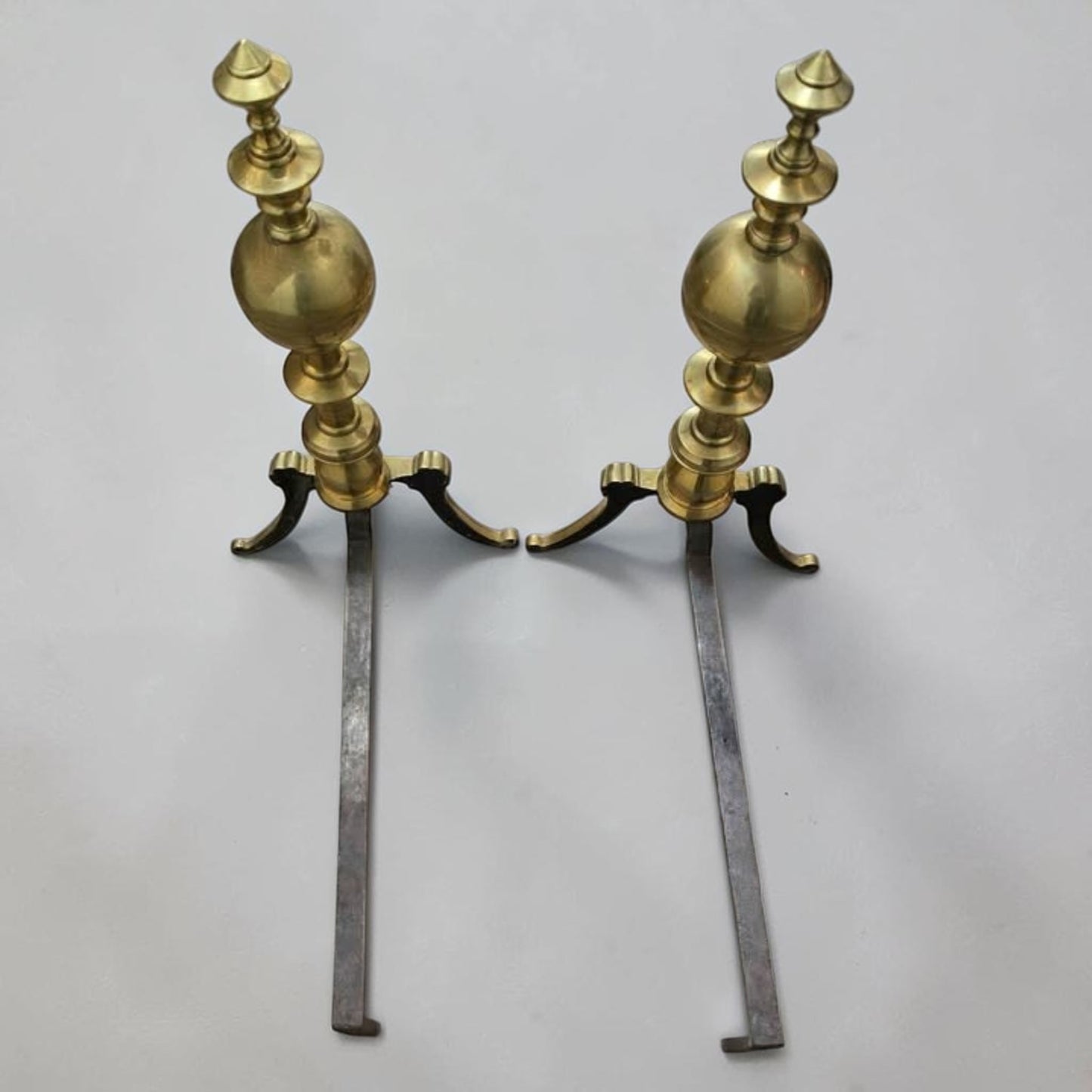 Antique brass and iron ornate fireplace andirons used as decorative hearth log holders.