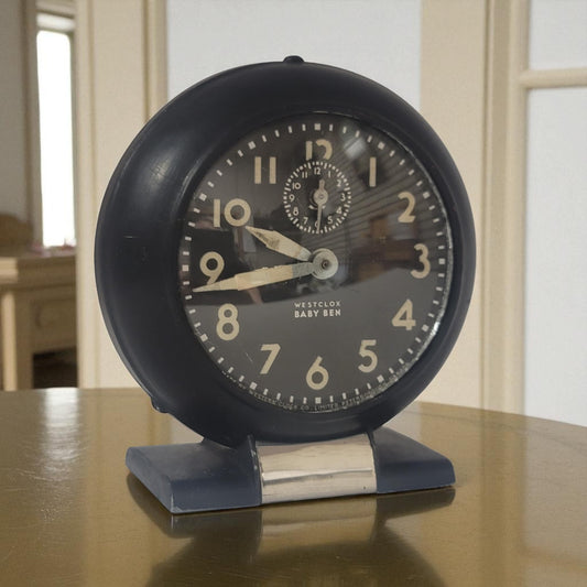 Vintage-style black alarm clock on a wooden surface with a neutral background
