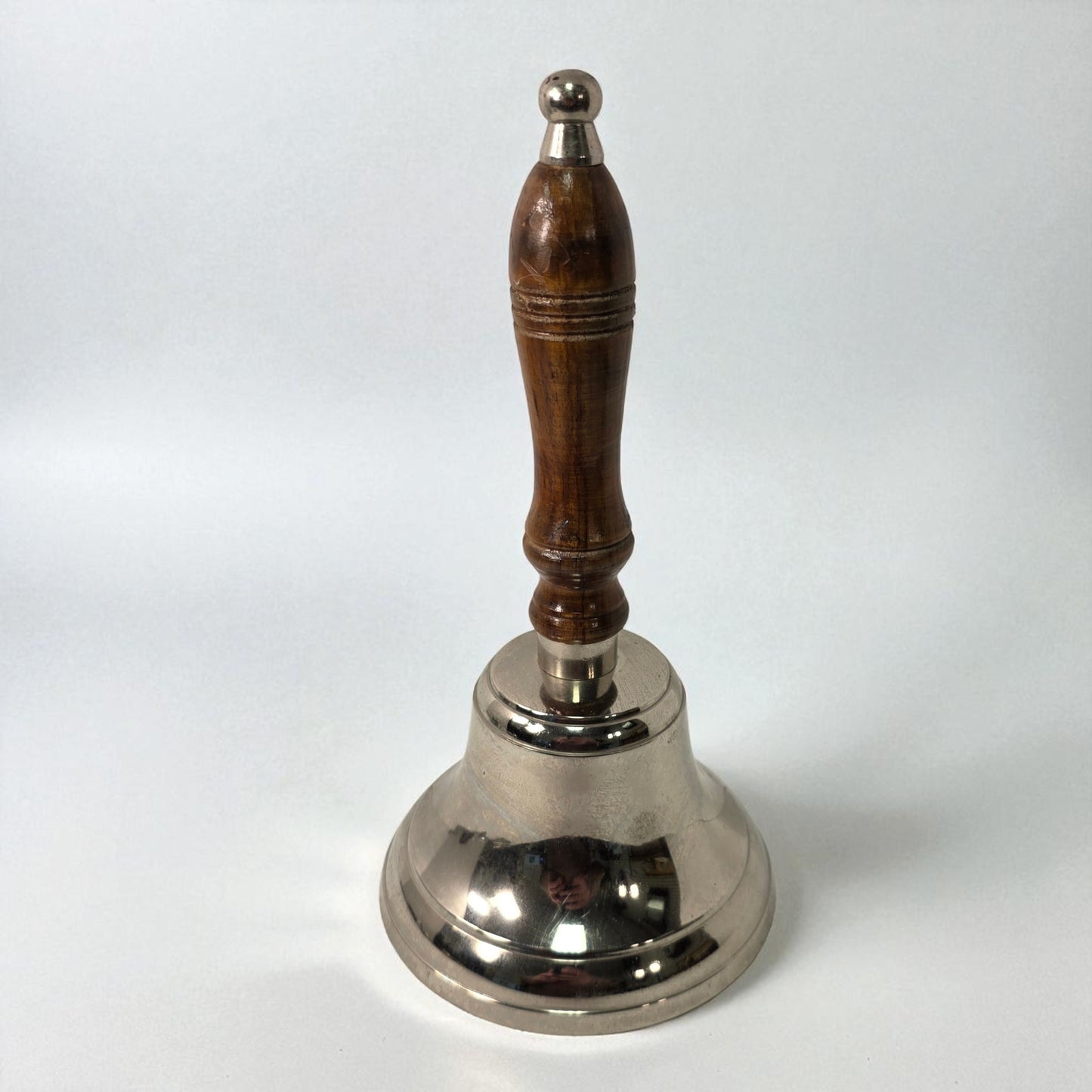 Silver bell with a wooden handle on a white background
