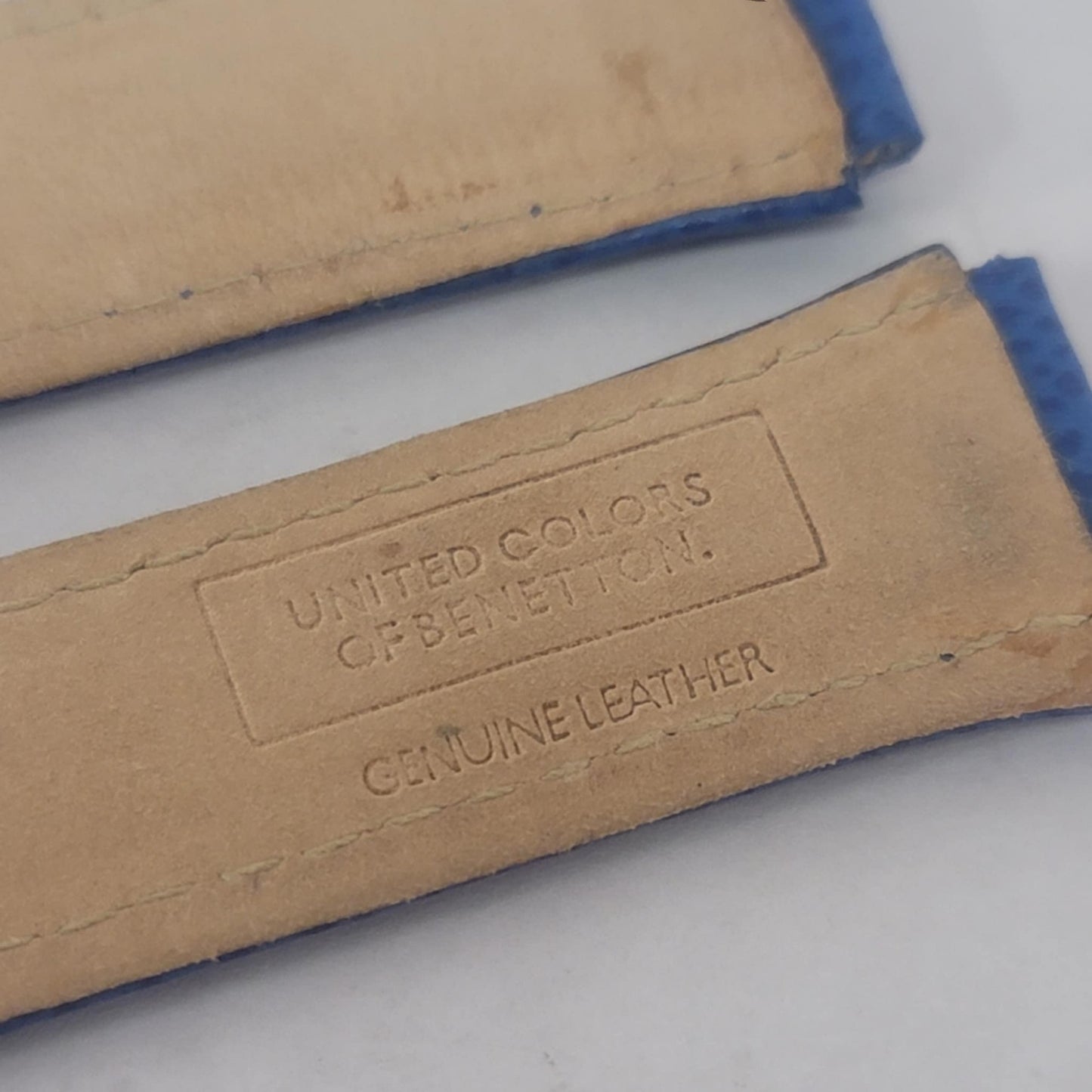 Close-up of a leather product with 'United Colors of Benetton' branding on a light background