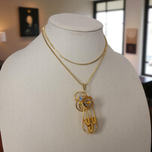 Gold necklace with a pendant on a mannequin bust in an indoor setting