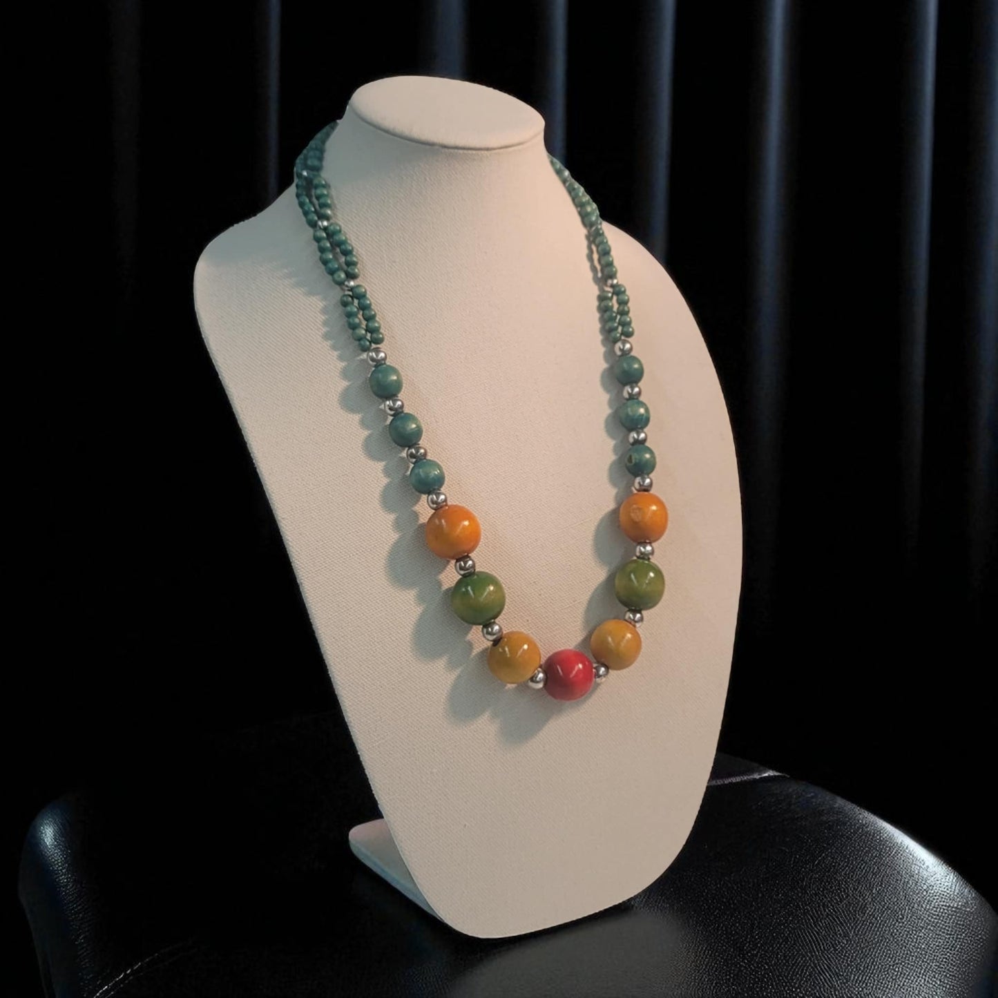 Necklace with multicolored beads on a white mannequin against a black background
