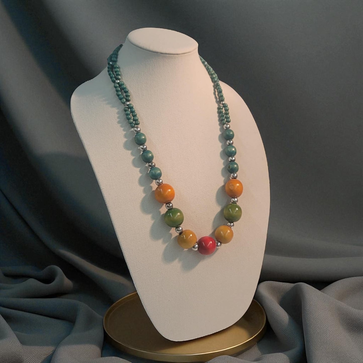 Necklace with multicolored beads on a mannequin bust against a gray background