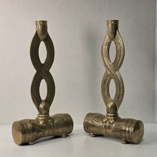 Pair of brass figure-eight candle holders with Egyptian-style engraved detailing.