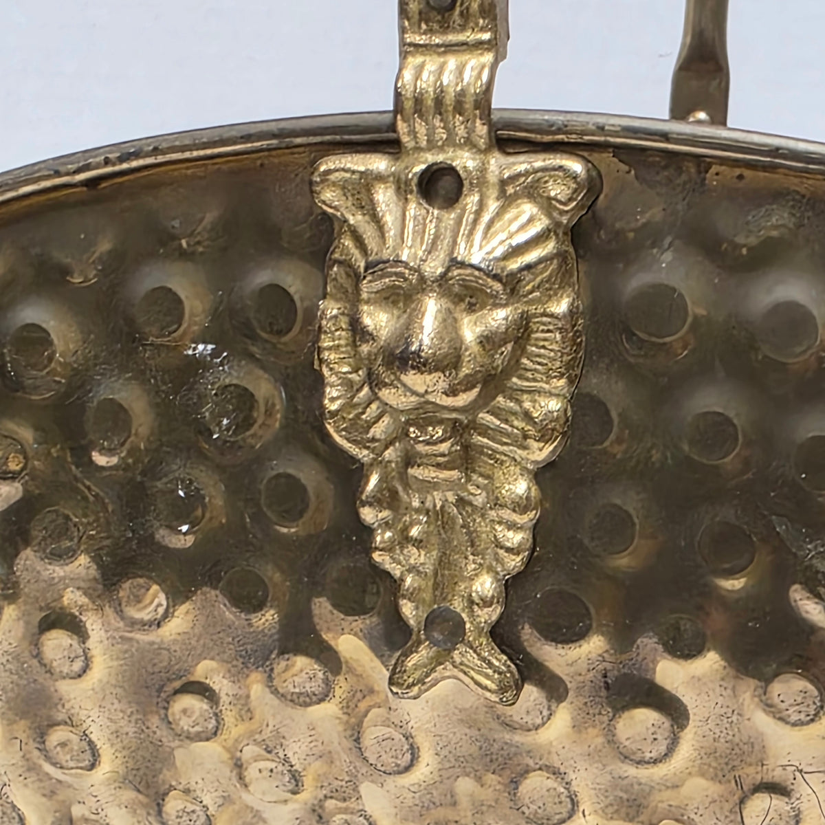 Ornate brass fireplace log holder with lion heads and paw feet