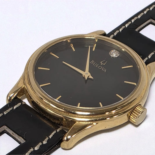 Bulova watch with gold case and black strap on a white background