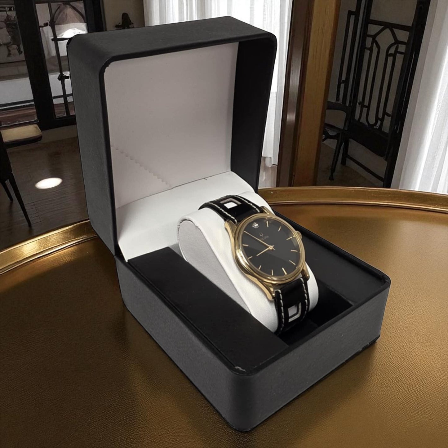Gold watch in a black display box on a wooden surface