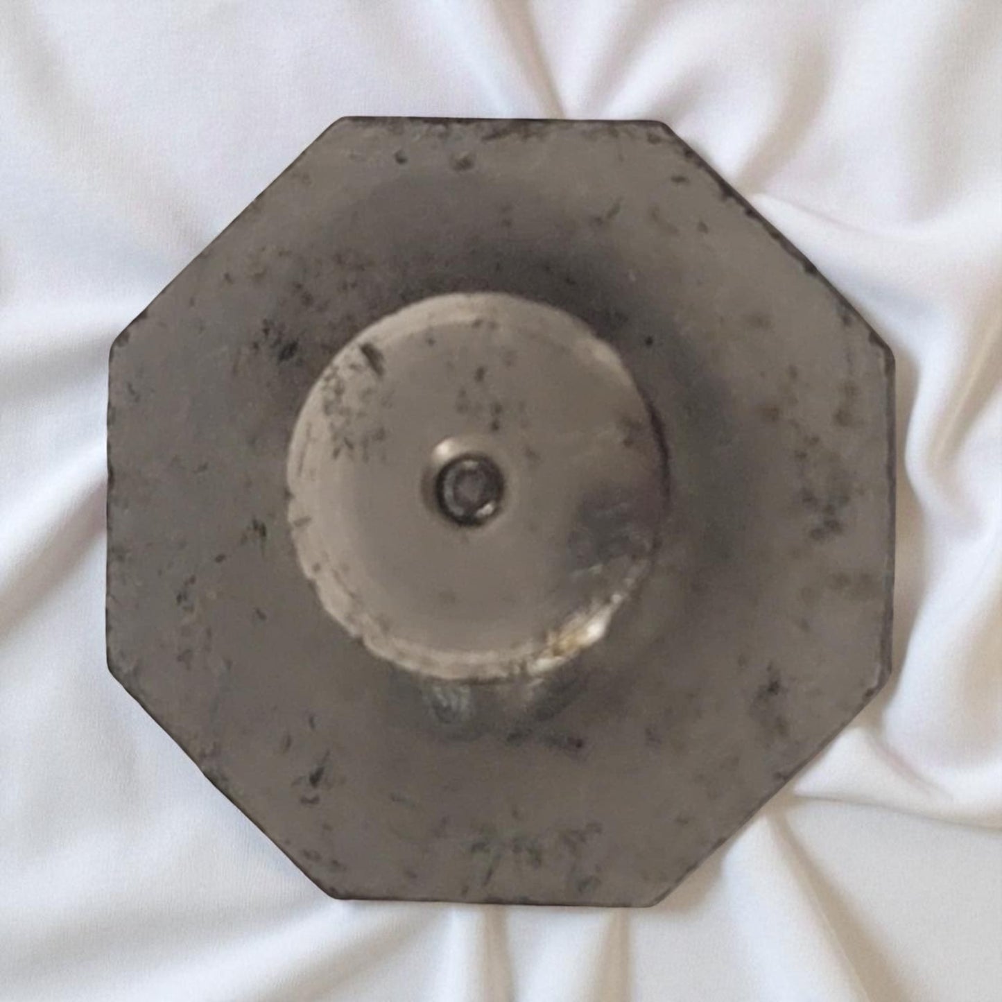 Hexagonal metal object on a white fabric background