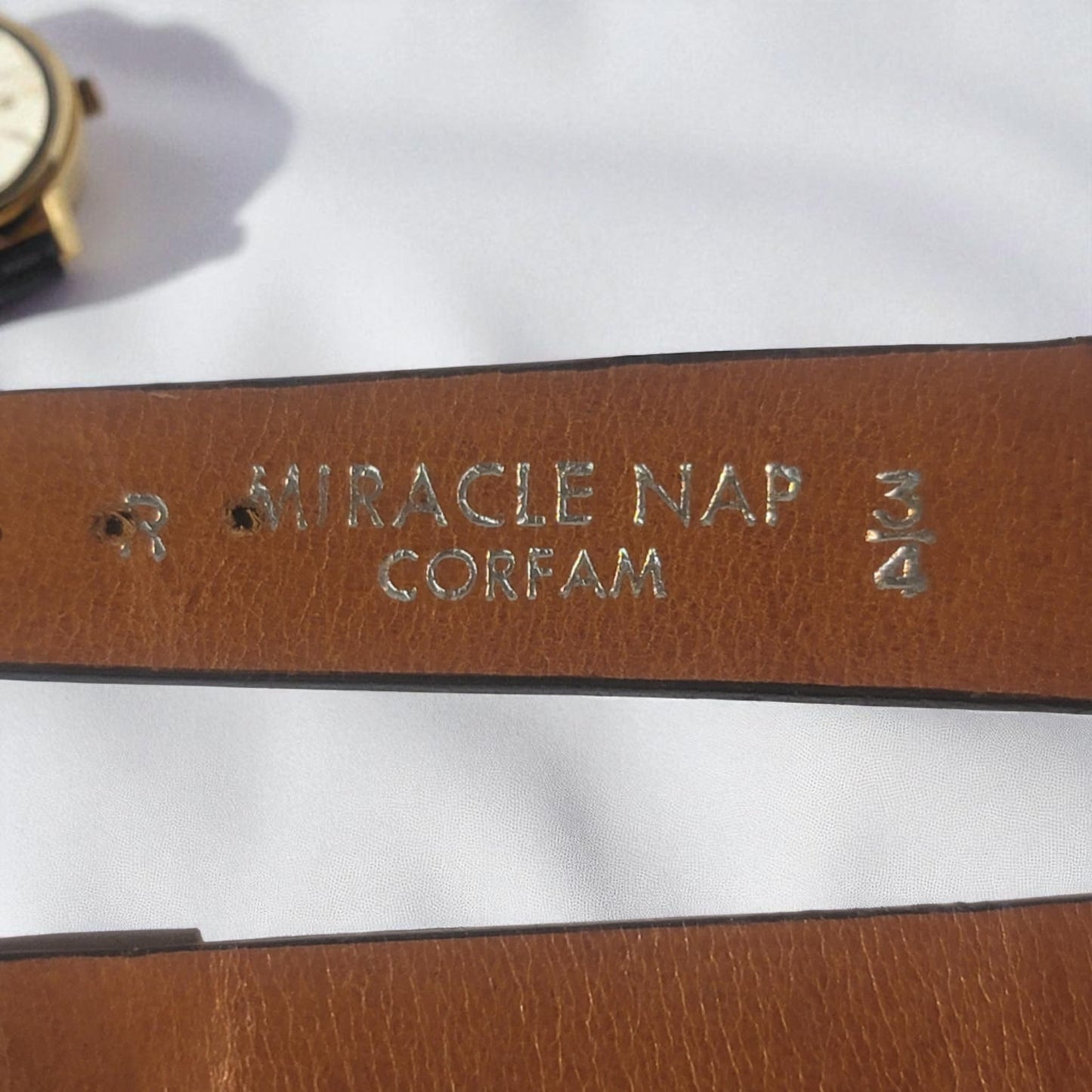 Brown leather strap with embossed text on a white background