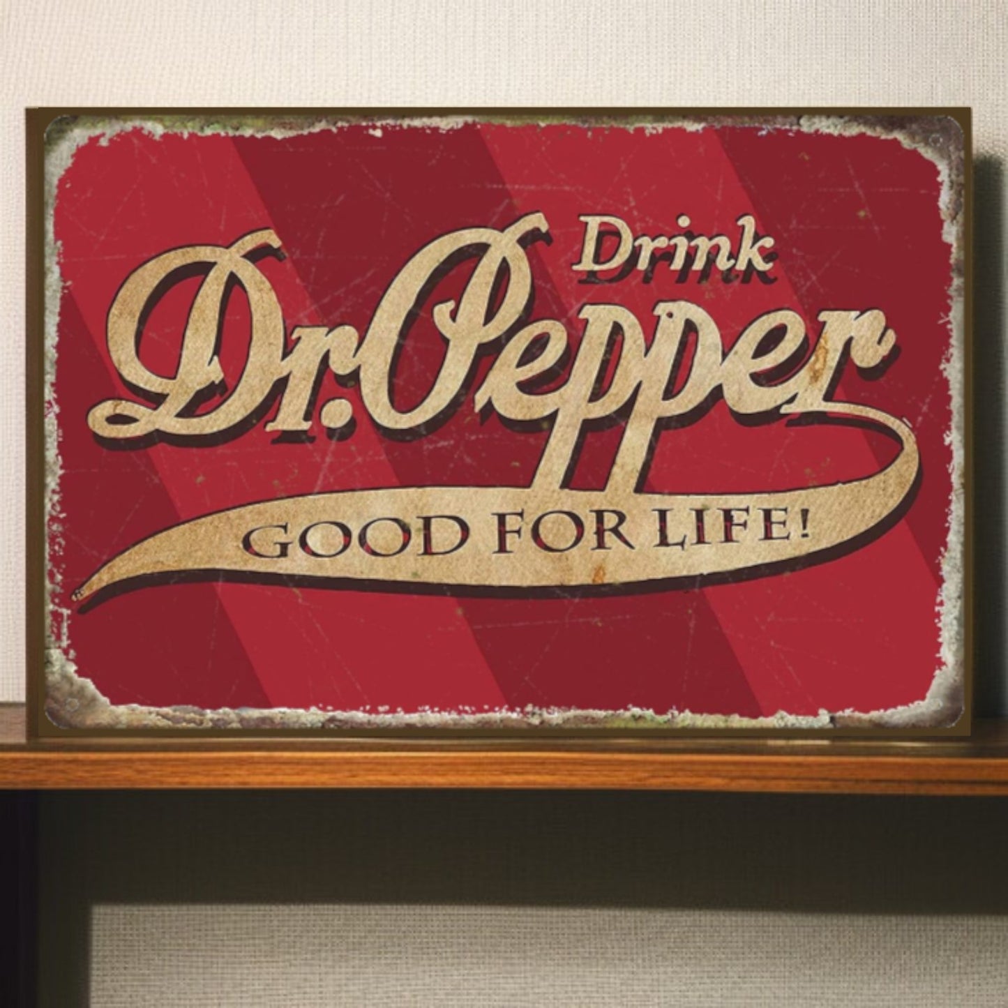 Vintage-style Dr. Pepper sign with red background and gold text on a wooden shelf.