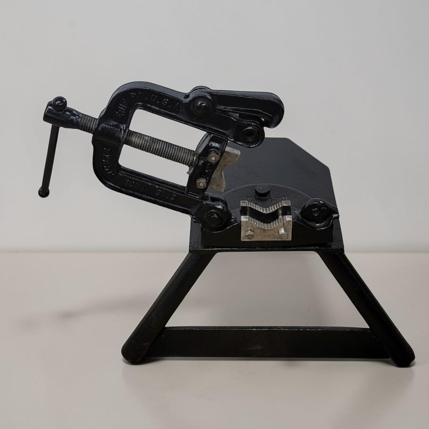 Erie Tools heavy duty pipe vise mounted on stand used for industrial plumbing and pipe clamping work.