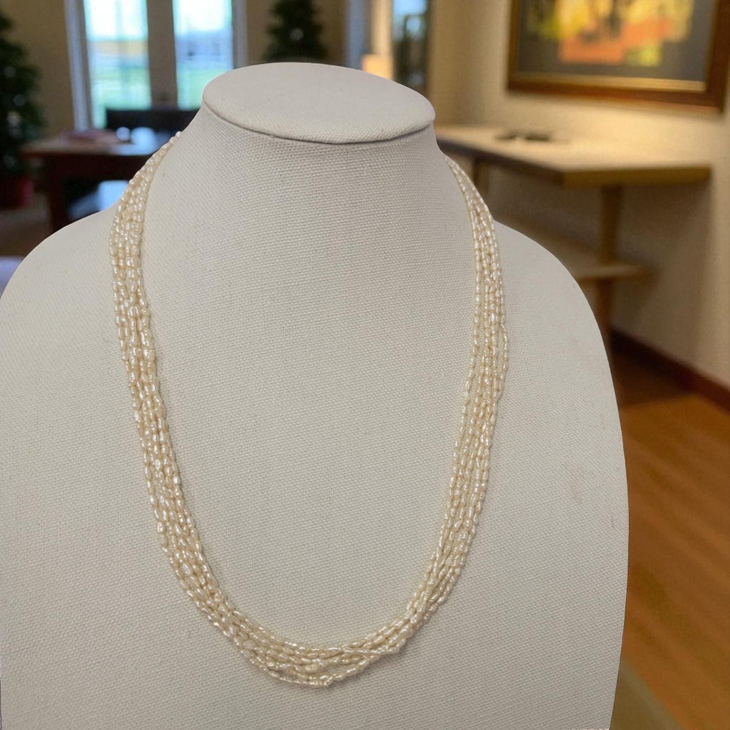 Pearl necklace on a mannequin bust with a blurred indoor background