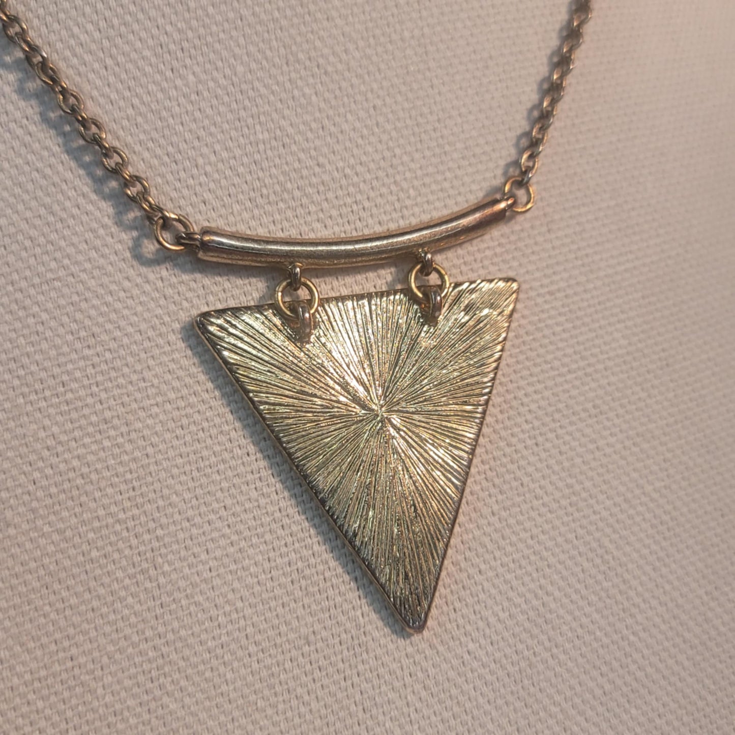 Necklace with a textured triangle pendant on a neutral background