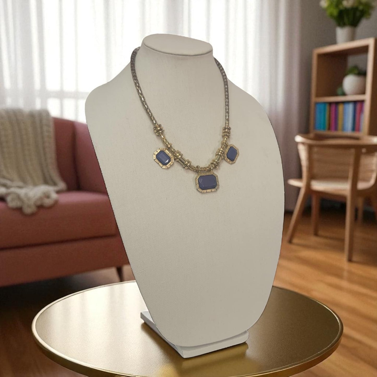 Necklace on a mannequin bust in a room with a couch and bookshelf.