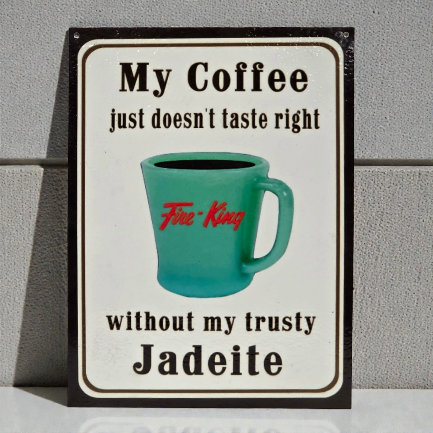 Sign with a teal mug and text about coffee and Jadeite on a gray background