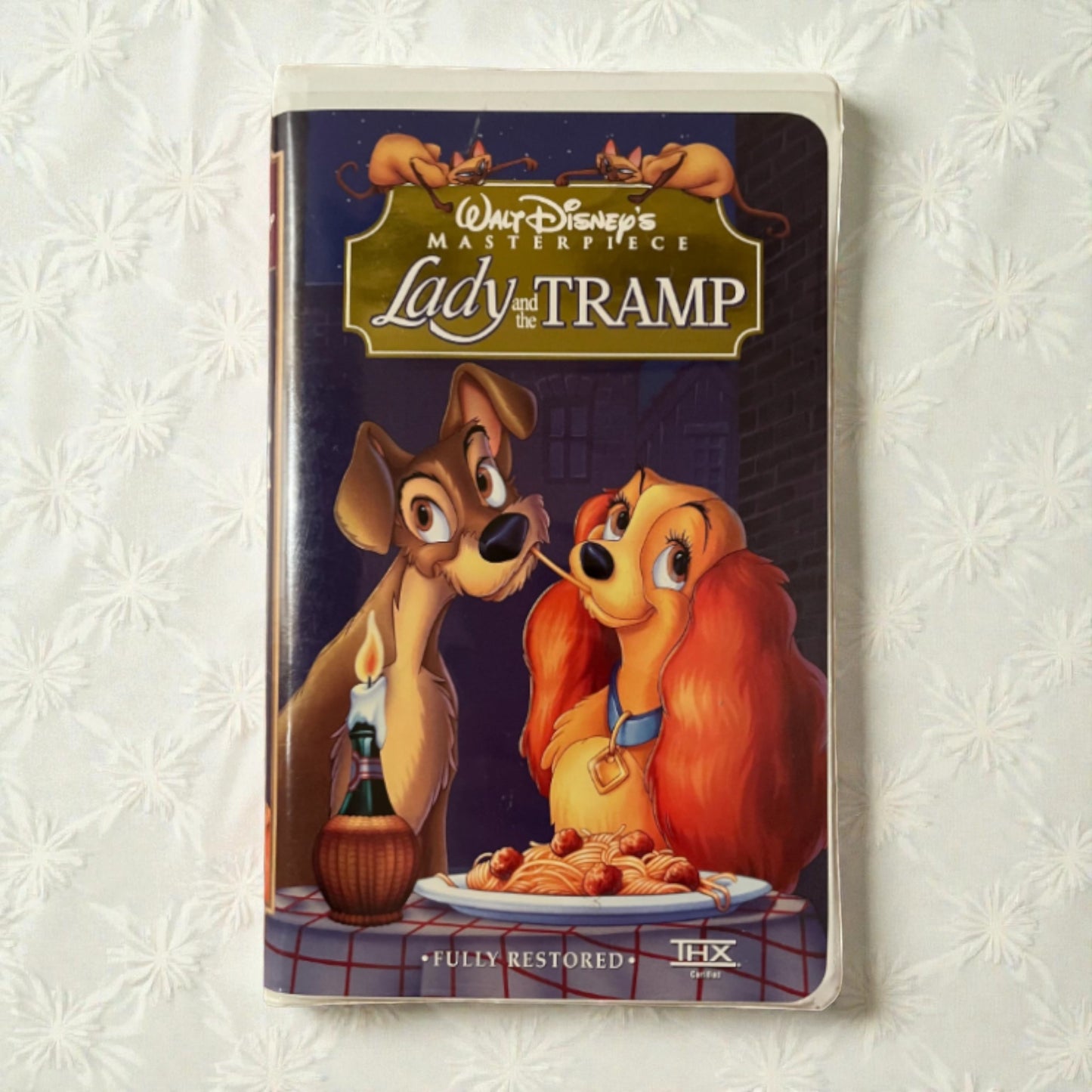VHS tape cover of 'Lady and the Tramp' with two dogs at a table on a textured white background