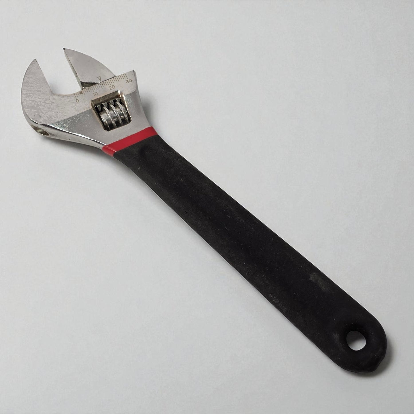 Adjustable wrench with black handle on a light gray background