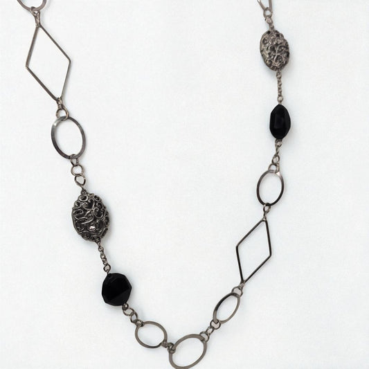 Necklace with geometric metal links and black beads on a white background