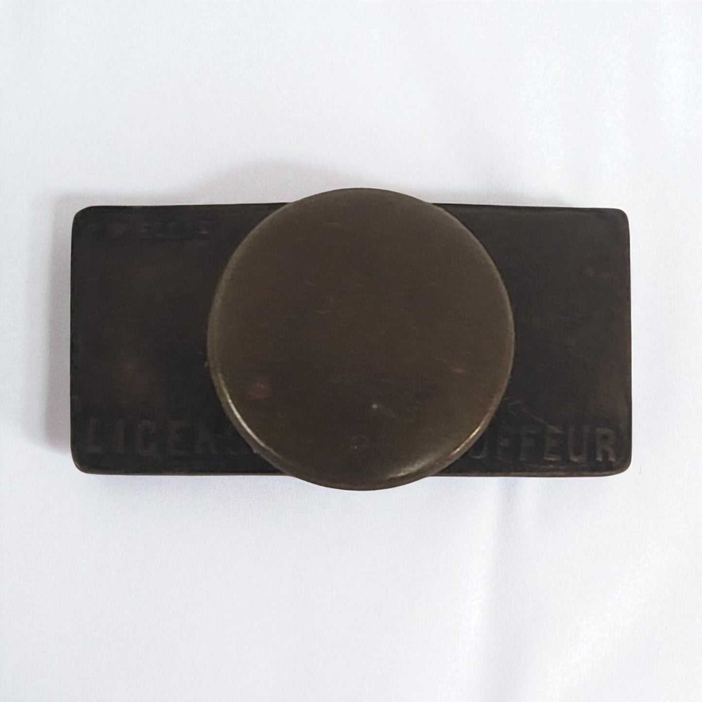 Round metal object on a rectangular black base with 'LICORE' and 'COFFEUR' text on a white background