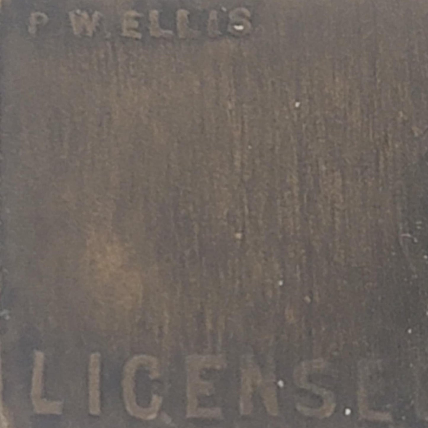 Close-up of a textured surface with engraved text 'P.W. ELLIS' and 'LICENSE'.