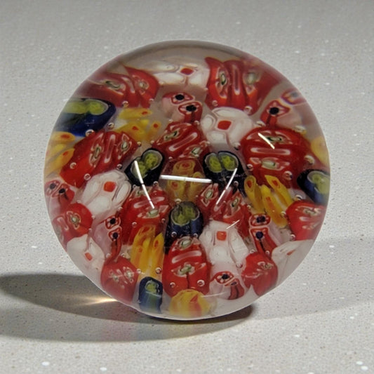 Colorful glass paperweight with a millefiori design on a gray background