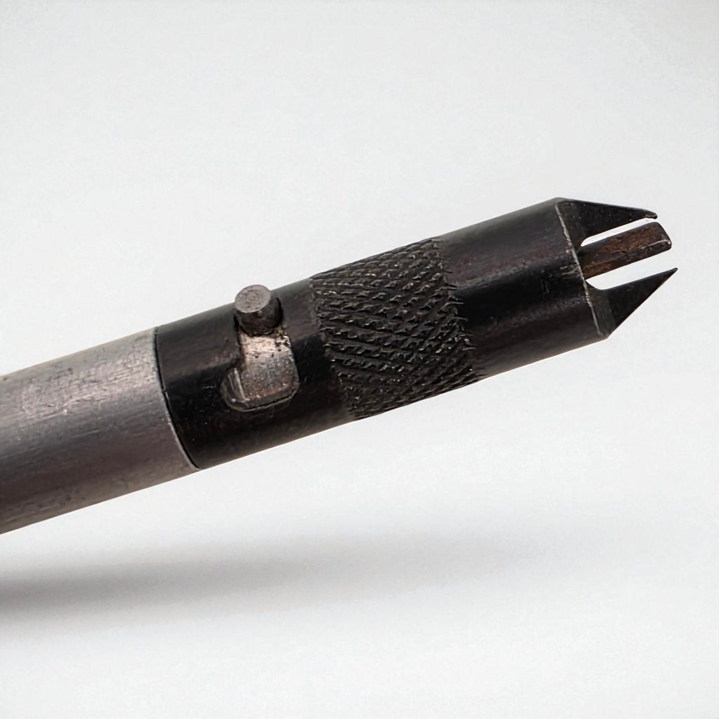Close-up of a metal tool with a textured handle on a white background