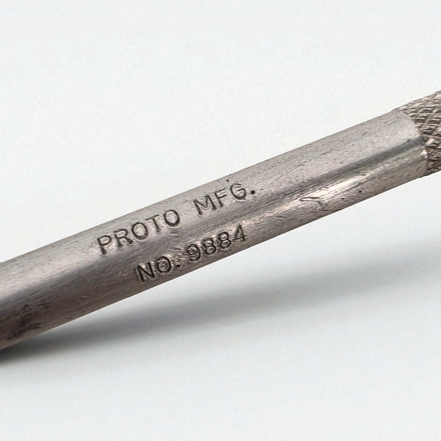 Metal rod with 'PROTO MFG.' and 'NO. 9884' engraving on a white background