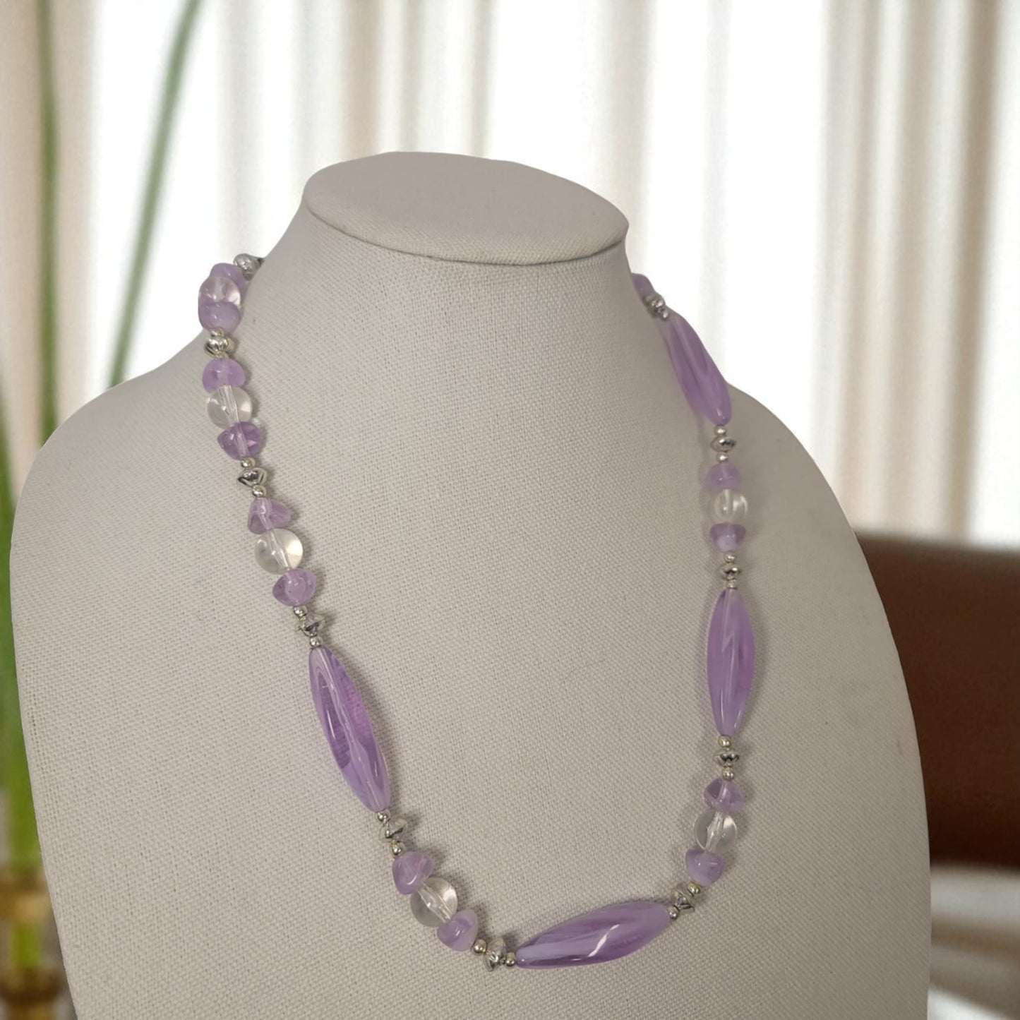 Necklace with purple beads on a mannequin bust against a neutral background