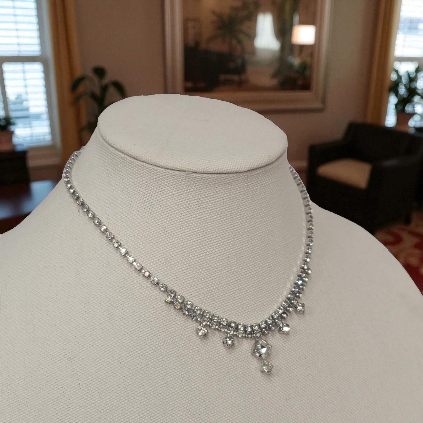 Silver necklace on a mannequin bust with a blurred indoor background