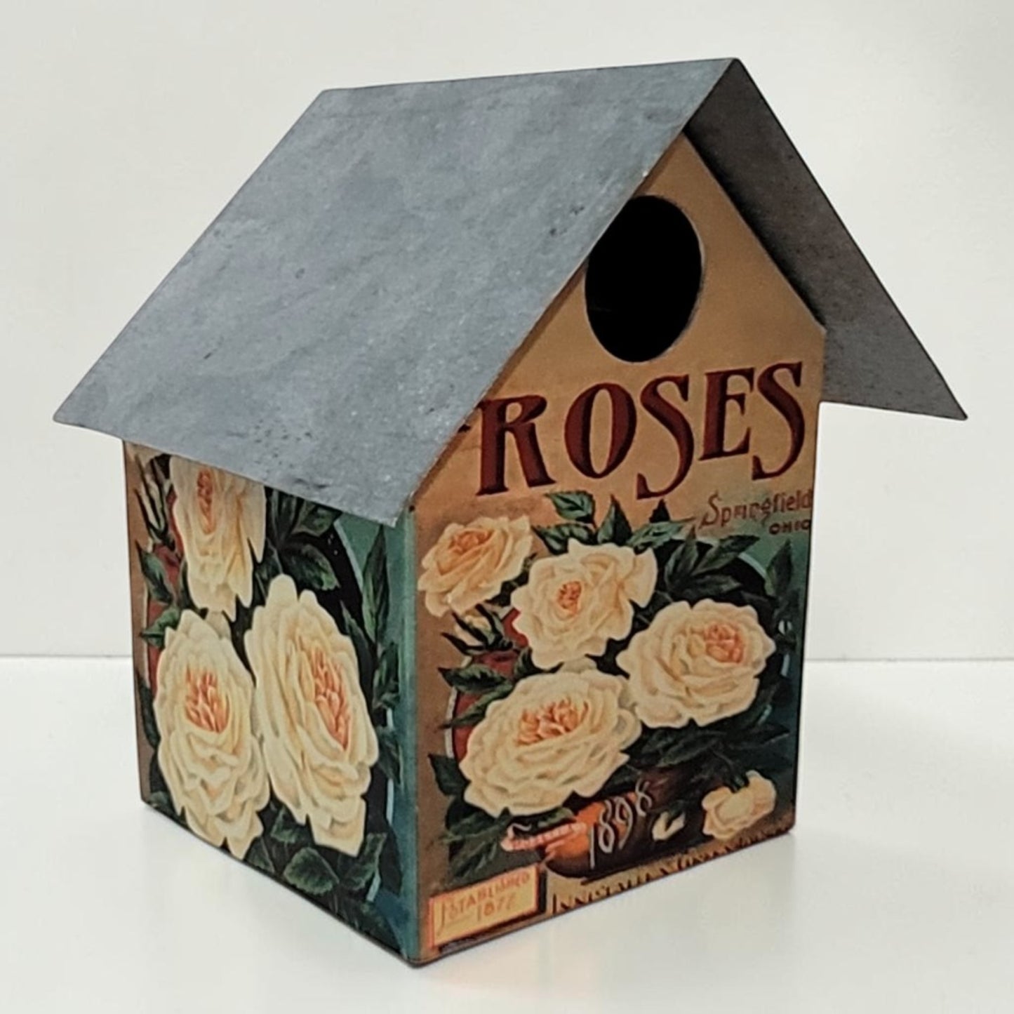 Handcrafted rustic rose-themed birdhouse made from reclaimed materials for garden and outdoor décor.
