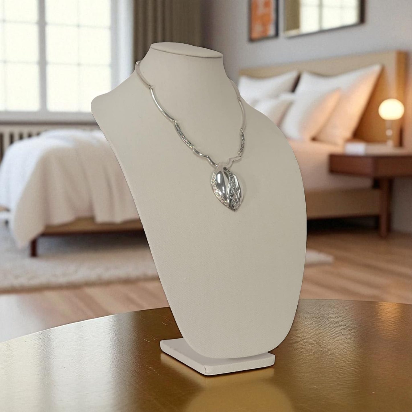 Necklace on a white bust in a bedroom setting