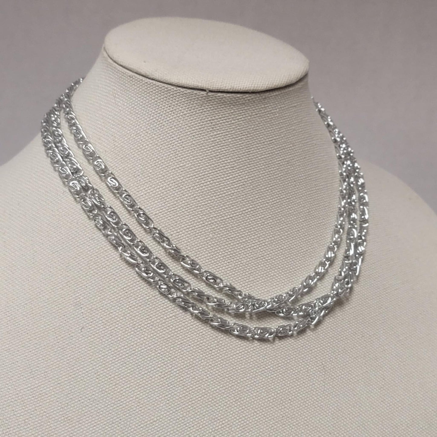 Silver chain necklace on a mannequin bust against a neutral background