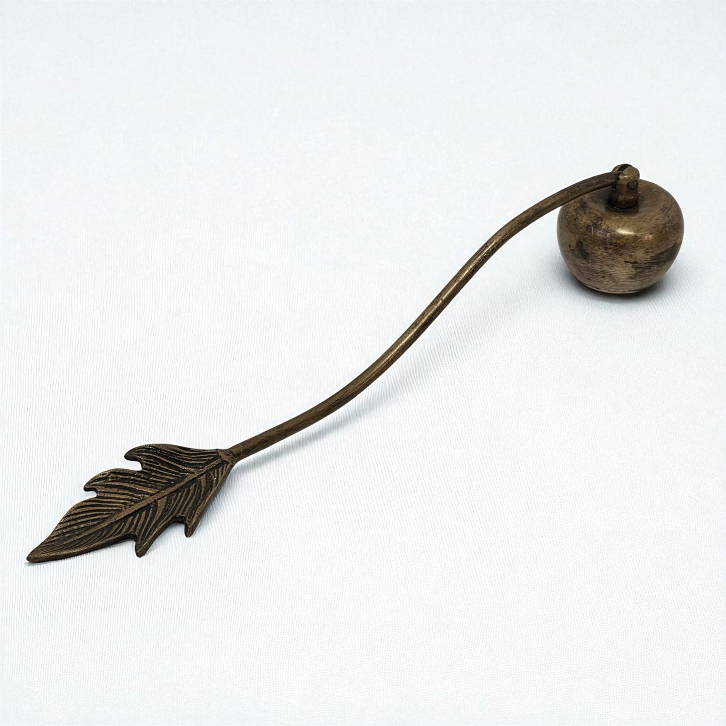 Bronze candle snuffer with leaf design on a white background