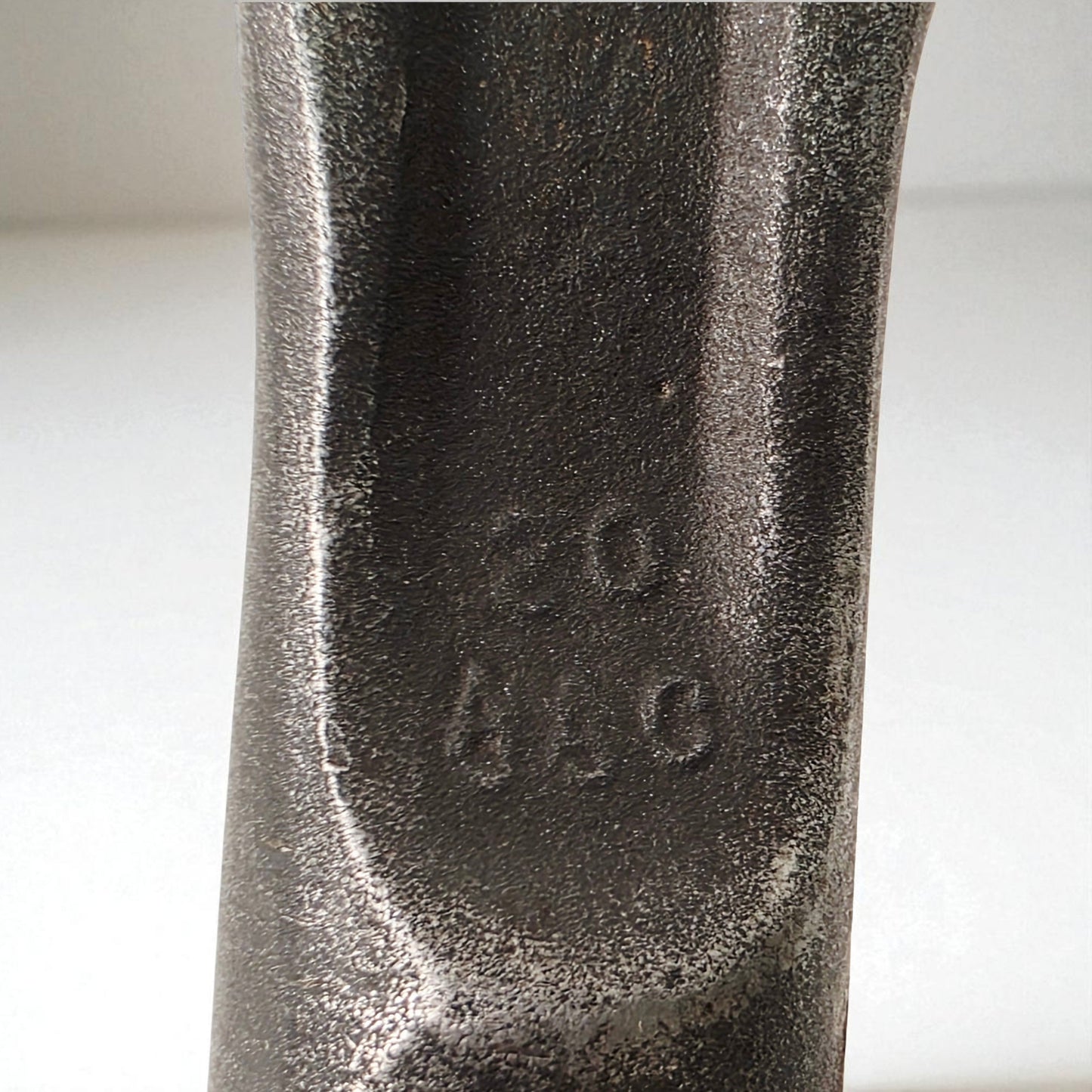 Close-up of a textured metal object with engraved numbers on a white background