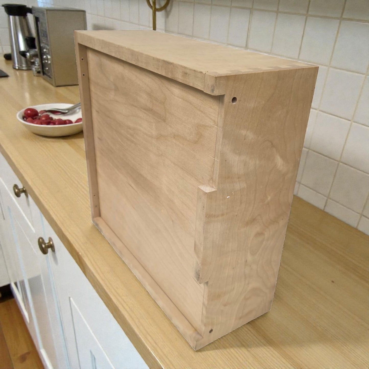 Wooden cabinet on a kitchen counter with a tiled wall in the background