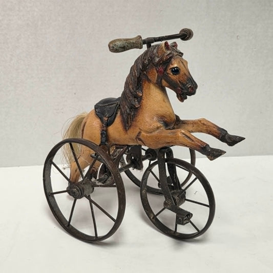Vintage miniature wooden toy horse ride-on velocipede with carved wooden body, iron wheels, and pedals. Antique collectible toy display piece from a bygone era.