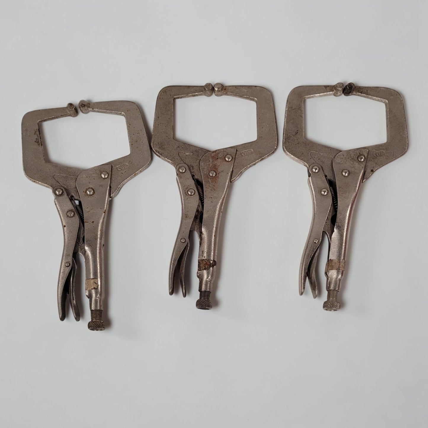 Set of three 11 inch C-clamp locking pliers used for welding and metal fabrication in a workshop setting.