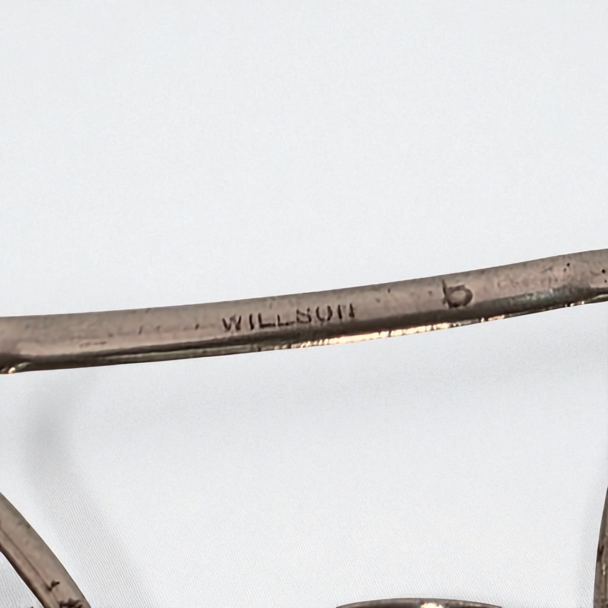 Close-up of a metallic object with 'WILSON' branding on a white background