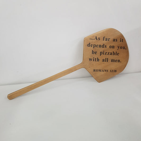 Vintage wooden pizza peel with “Be Pizza-ble with All Men” script.