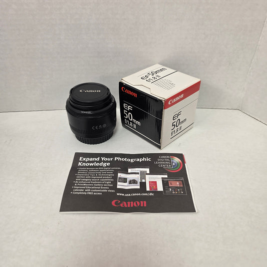 Canon camera lens with packaging and leaflet on a textured surface