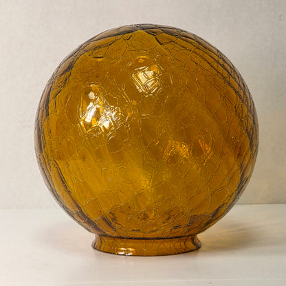 Vintage amber glass crinkle lamp globe casting a warm, patterned glow.