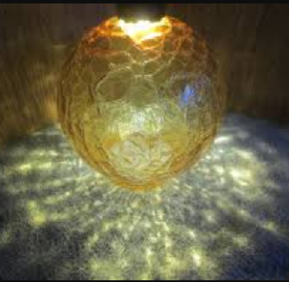 Vintage amber glass crinkle lamp globe casting a warm, patterned glow.