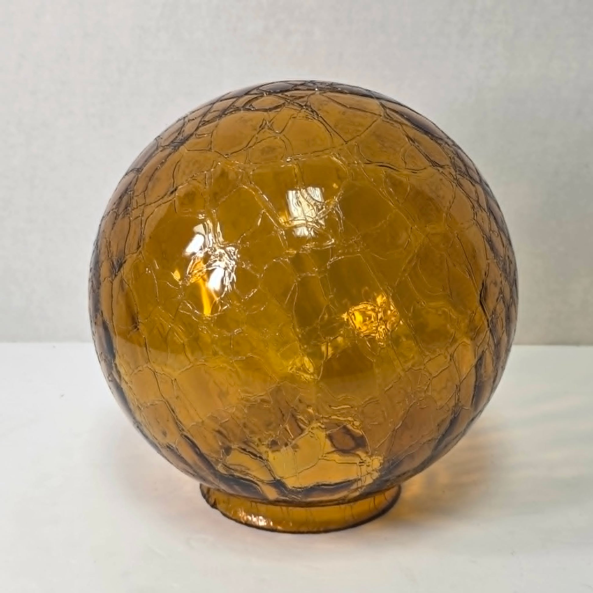 Vintage amber glass crinkle lamp globe casting a warm, patterned glow.