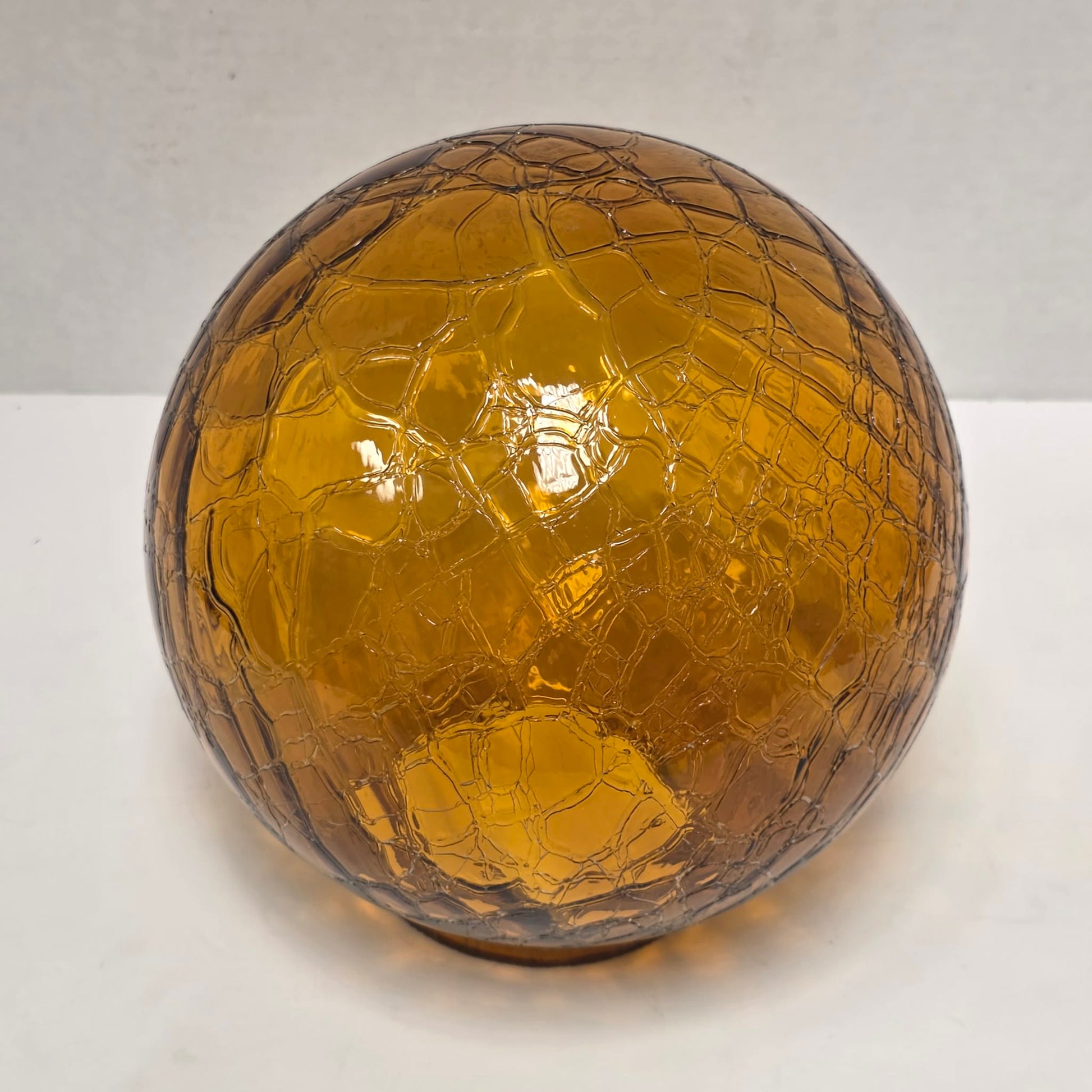 Vintage amber glass crinkle lamp globe casting a warm, patterned glow.